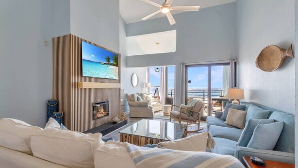 A modern living room with a fireplace, a sofa, a coffee table, and a view of the sea.