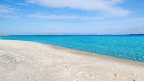 A beach with clear turquoise water and a sandy shore.