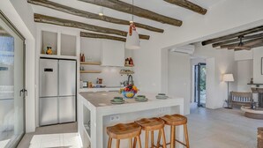 A modern kitchen with a central island, wooden stools, and a hanging pendant light. - Jujube - Javea, Costa Blanca (Javea)