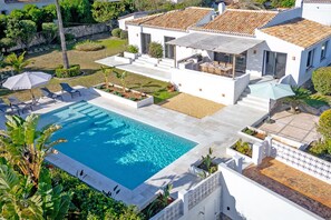 A modern house with a swimming pool, outdoor seating, and a well-maintained garden.