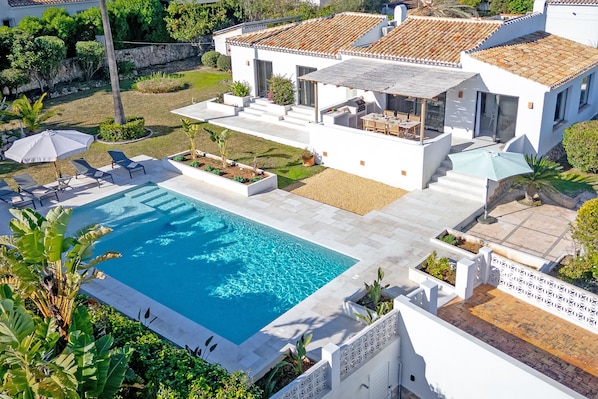 Relax by the pool surrounded by a beautiful garden and patio area.