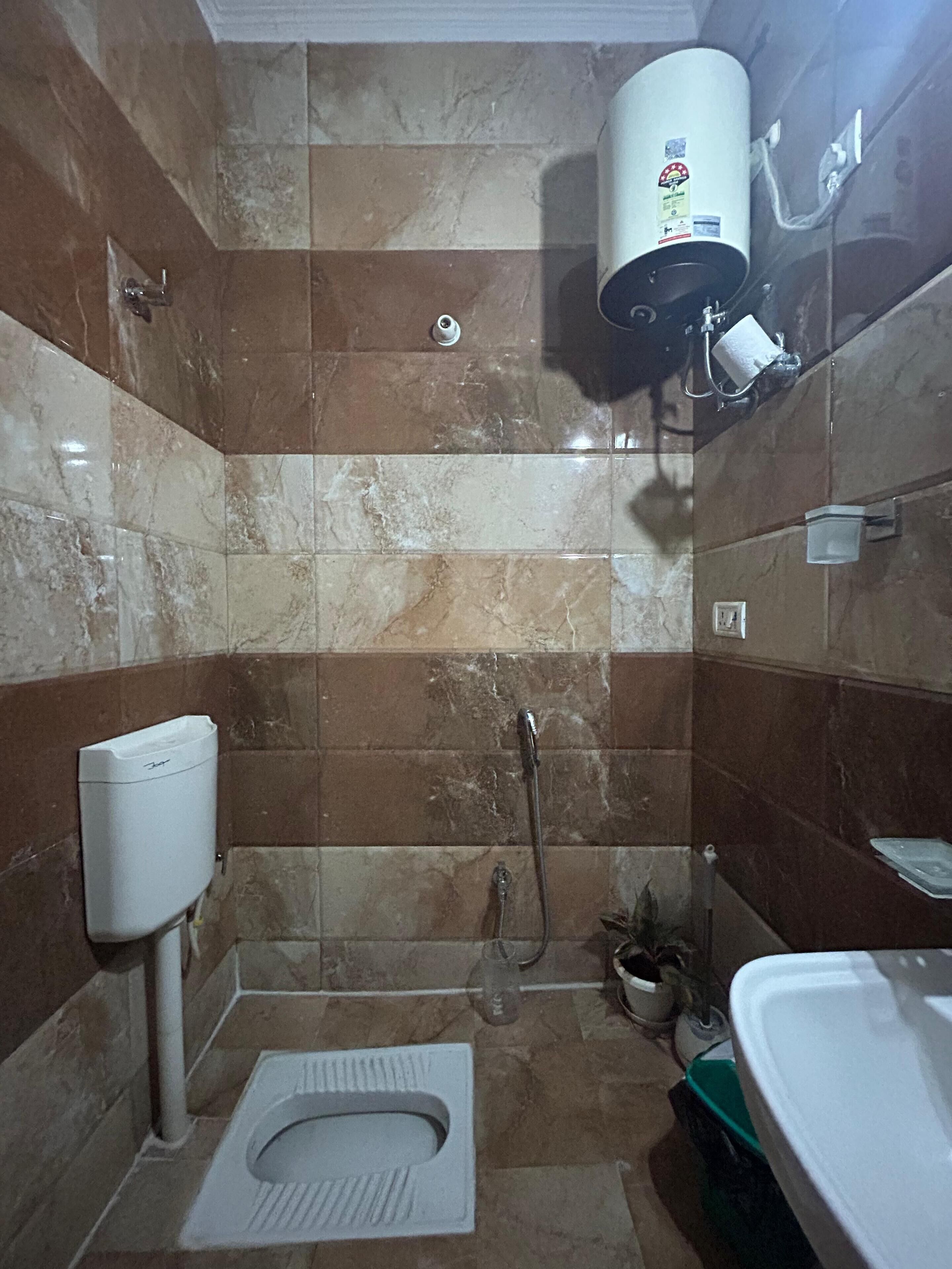 A bathroom with a toilet, a shower, and a hand dryer.