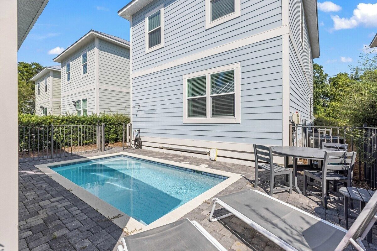 A residential property with a swimming pool, outdoor seating, and a fenced yard.