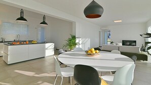 A modern kitchen with white cabinetry, a central island, and pendant lighting. - Villa Brezza: A bright and sunny three-story villa situated in a quiet location, a few minutes from the town center, with Free WI-FI. (Giarre)