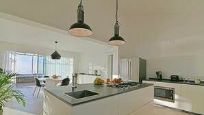 A modern kitchen with a central island, stainless steel appliances, and a dining area with a view. - Villa Brezza: A bright and sunny three-story villa situated in a quiet location, a few minutes from the town center, with Free WI-FI. (Giarre)