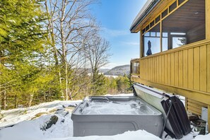 Relax in a hot tub surrounded by serene winter scenery and majestic mountains.