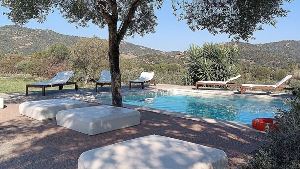 A pool area with lounge chairs and a view of mountains.