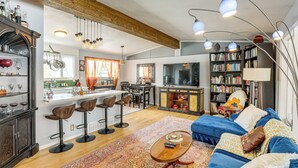 Un ampio soggiorno con divano, tavolino e libreria. È presente un'area cucina con tavolo e sedie.