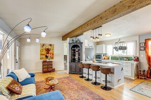 A spacious living area with a sofa, a coffee table, and a kitchen with a bar stool area. - 10 Mi to Red Rocks: Denver Home w/ Fire Pit! (Denver)