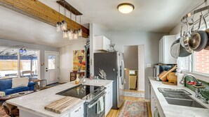 Una cucina moderna con isola centrale, elettrodomestici in acciaio inossidabile e pentole appese.
