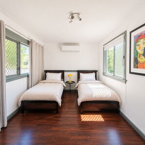 A hotel room with two beds, a small table with a lamp, and a window with curtains. - 4BR Central Dubbo Family Home, 2 Living Areas, Large Backyard, Sleeps 8 (Dubbo)
