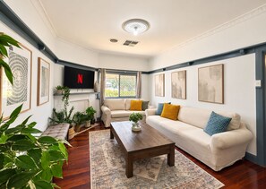 A living room with a sofa, coffee table, and a TV mounted on the wall.