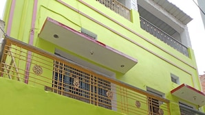 Ein zweistöckiges Gebäude mit einer leuchtend grünen Fassade, einem Balkon mit Metallgeländern und einer Tür mit Fenster.