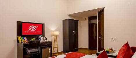 Ett hotellrum med en säng, ett skrivbord, en tv, en takfläkt och en dörr.