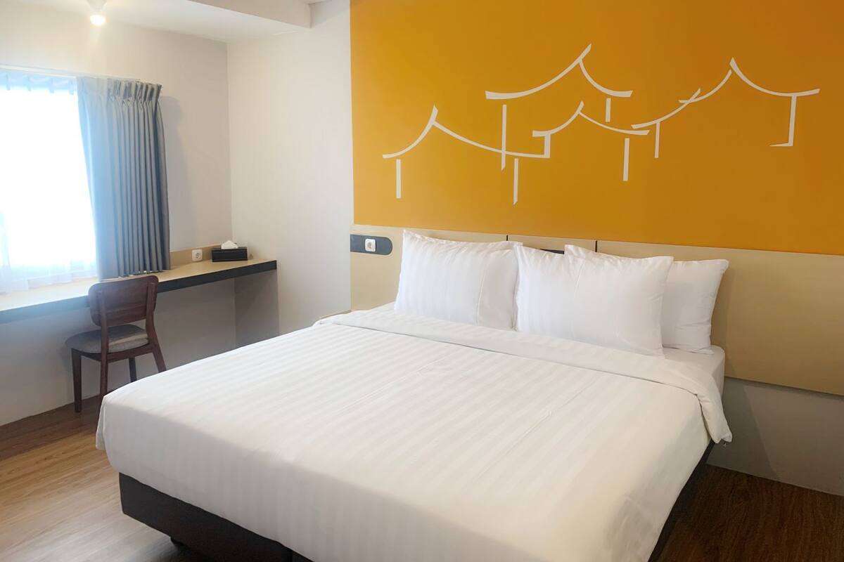 A hotel room with a bed, a desk, and a chair.