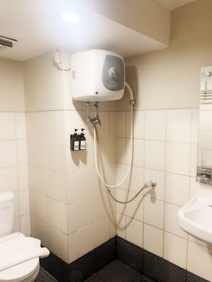 A bathroom with a white toilet, a sink, and a shower with a handheld showerhead. - Nemuru Stay BTC (Bekasi)