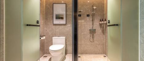 A modern bathroom with a toilet, a shower, and a glass partition.