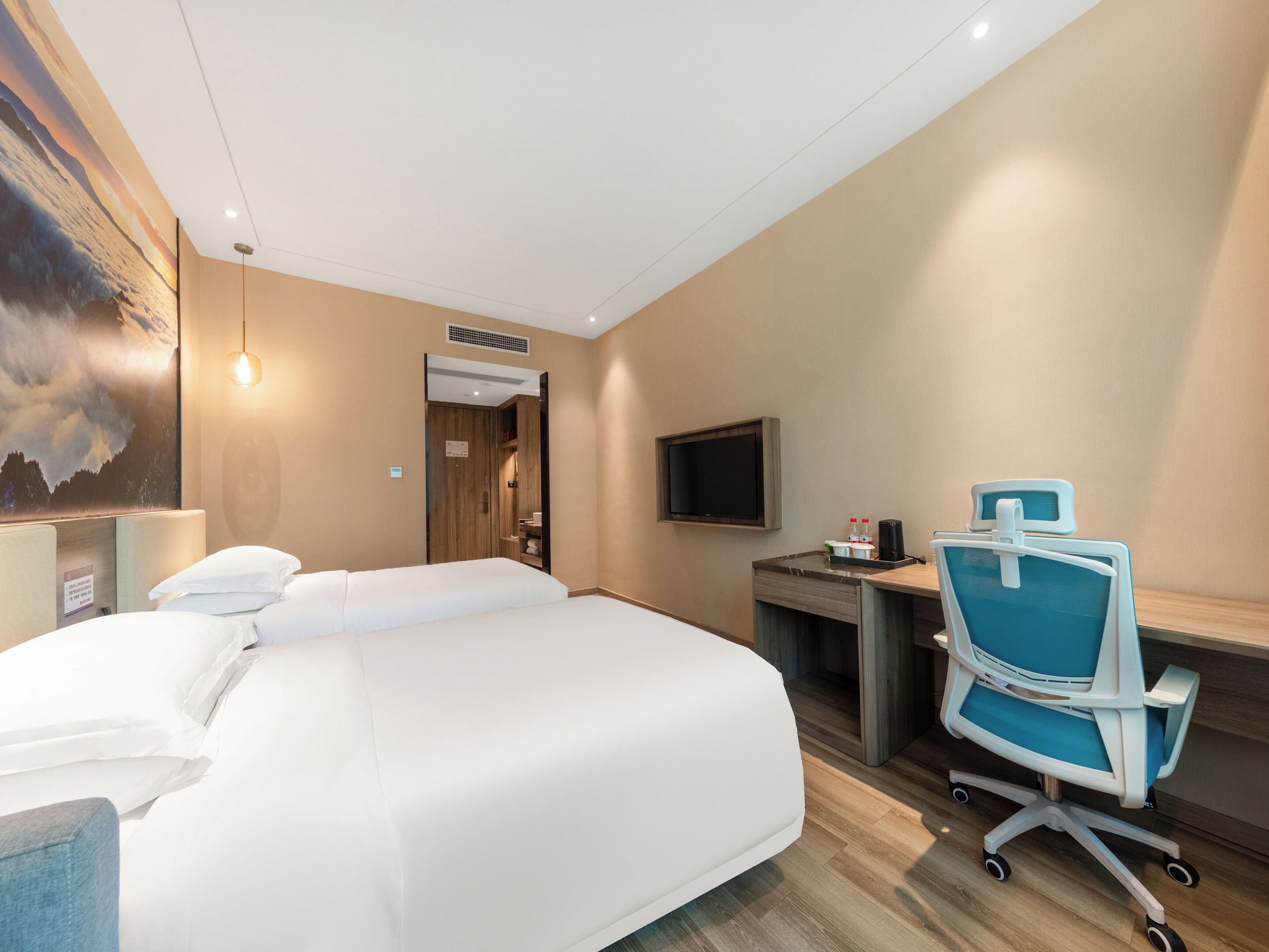 A hotel room with a bed, a desk, a chair, a TV, and a painting on the wall.