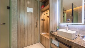 Un baño moderno con tocador de madera, un espejo grande y ducha integrada.