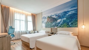 Habitación de hotel con dos camas, un escritorio, una silla y un cuadro con vistas a una gran montaña.