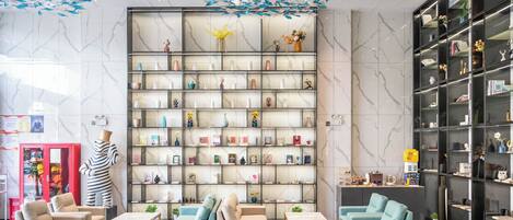 A modern lobby with marble walls, a large bookshelf, and seating areas.