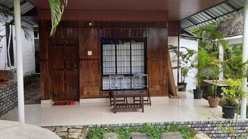 A covered wooden structure with a bench and potted plants.