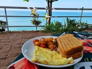 A plate of food with toast, eggs, and potatoes on a table with a view of the ocean. - Puthooram Sea View Resort Varkala (Varkala)