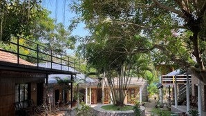 A courtyard with a wooden building, a stone pathway, and potted plants. - Puthooram Sea View Resort Varkala (Varkala)