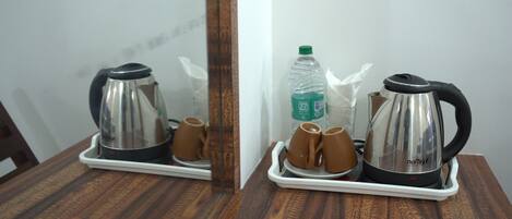 Una mesa de madera con una bandeja que contiene una tetera, dos tazas y una botella de agua.