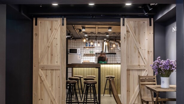 Una cocina moderna con detalles de madera, taburetes de bar e iluminación colgante.