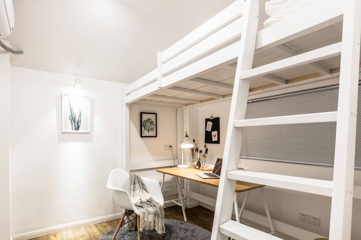 Una habitación con literas, un escritorio y una silla.