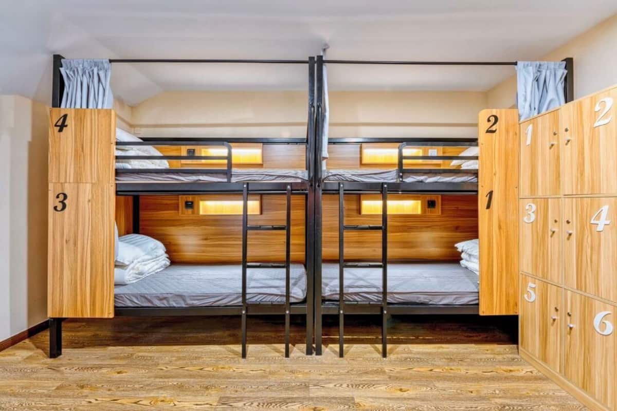 Habitación con literas de madera, una escalera central y un armario de madera con compartimentos numerados.