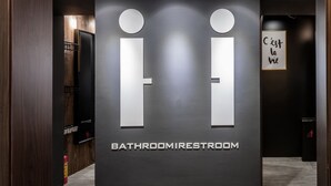 Un baño moderno con un diseño minimalista, que incluye un cartel con la inscripción 'BATHROOMRESTROOM' y la frase francesa 'C'est la vie' en la pared.