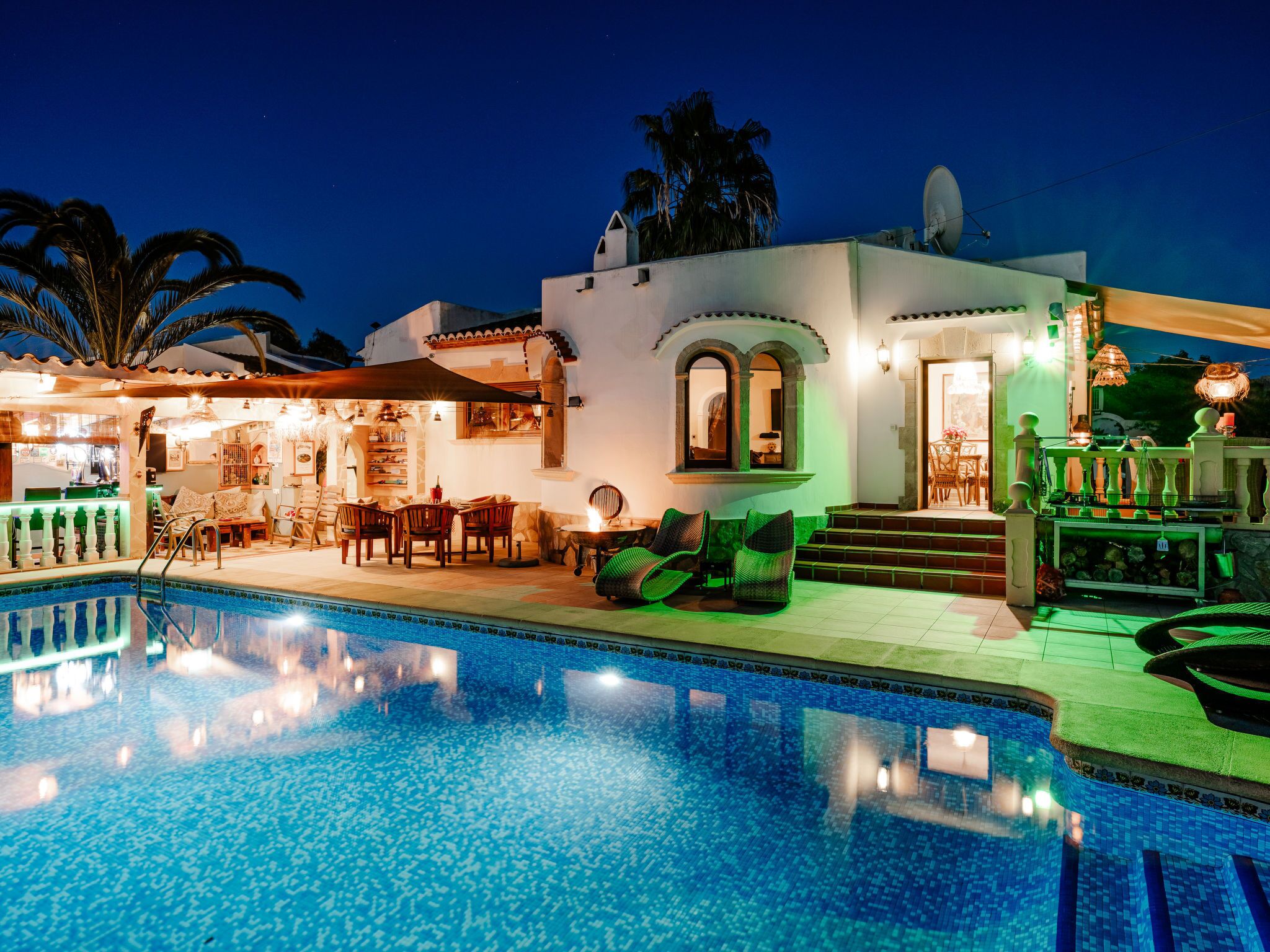 A poolside area with a bar, seating, and a staircase leading to the building.