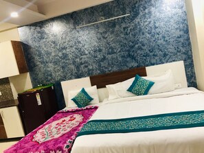 A hotel room with a large bed, white bedding, and a blue textured wall. - Basra Hotel - Gurgaon (Gurugram)
