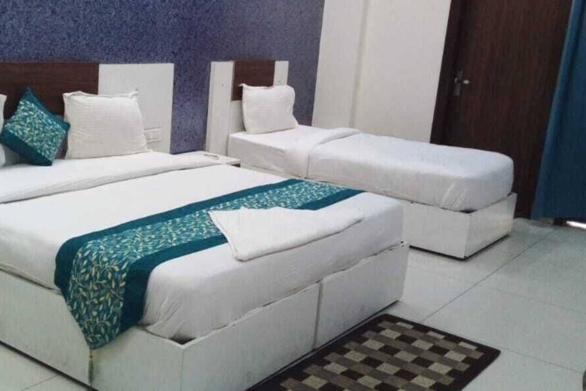 A hotel room with a large bed, a smaller bed, a bedside table, and a chair.