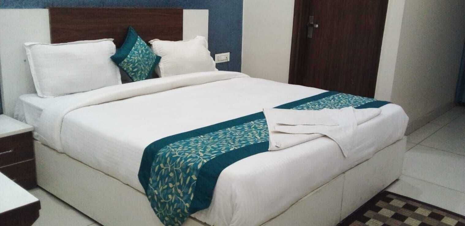 A neatly made bed with white linens and a teal patterned throw.