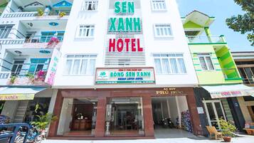 Um edifício de vários andares com a placa 'SEN XANH HOTEL' e 'BONG SEN XANH GREEN LOTUS HOTEL'.