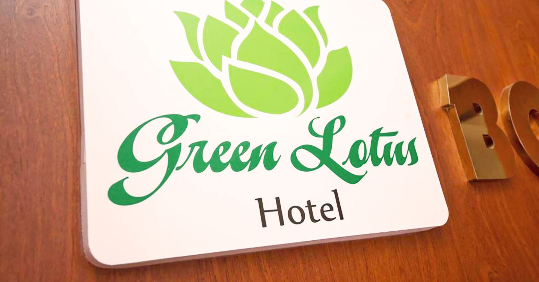 A hotel sign with the name "Green Lotus Hotel" and a lotus flower logo.