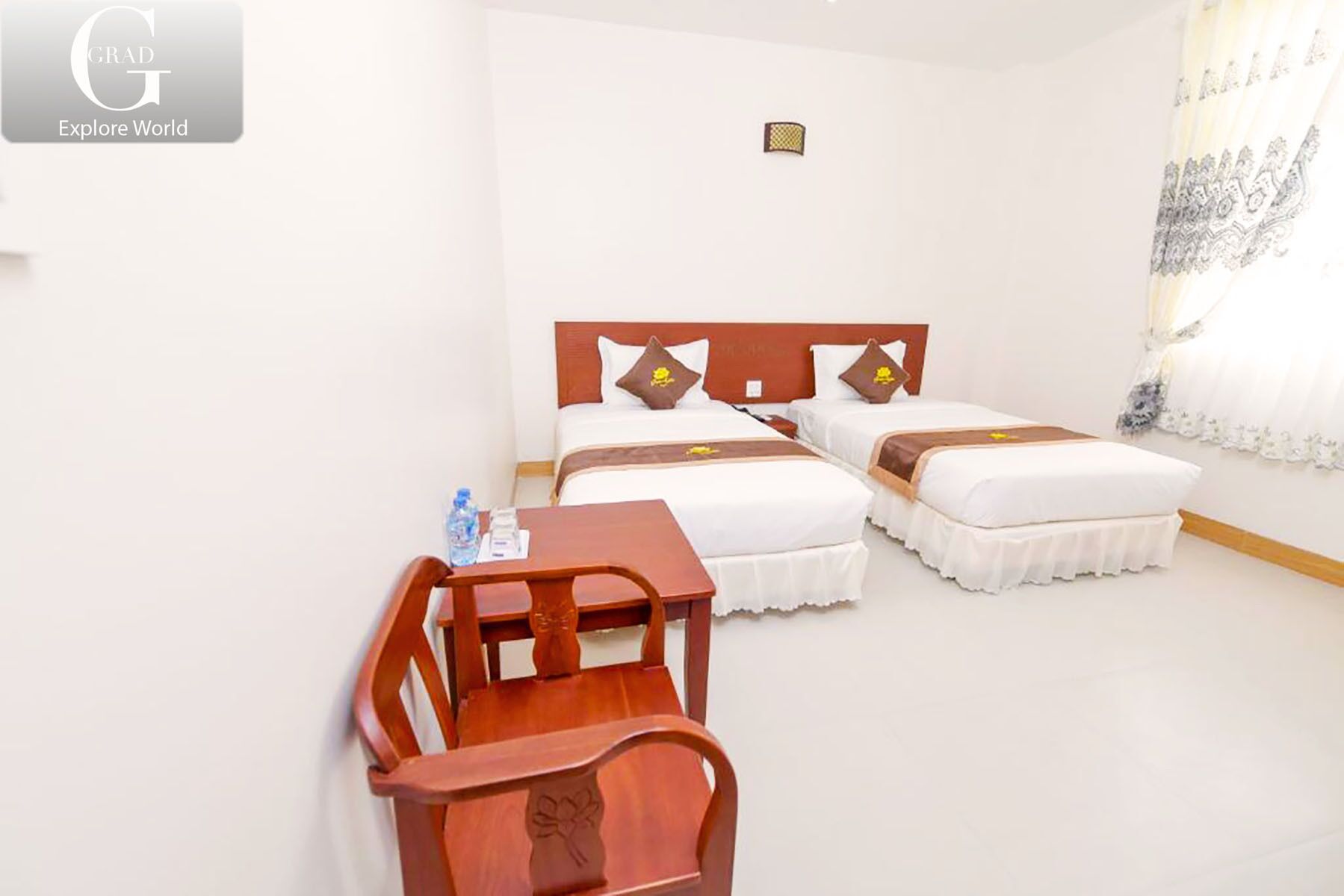 Une chambre d’hôtel avec deux lits, un bureau en bois et une chaise.