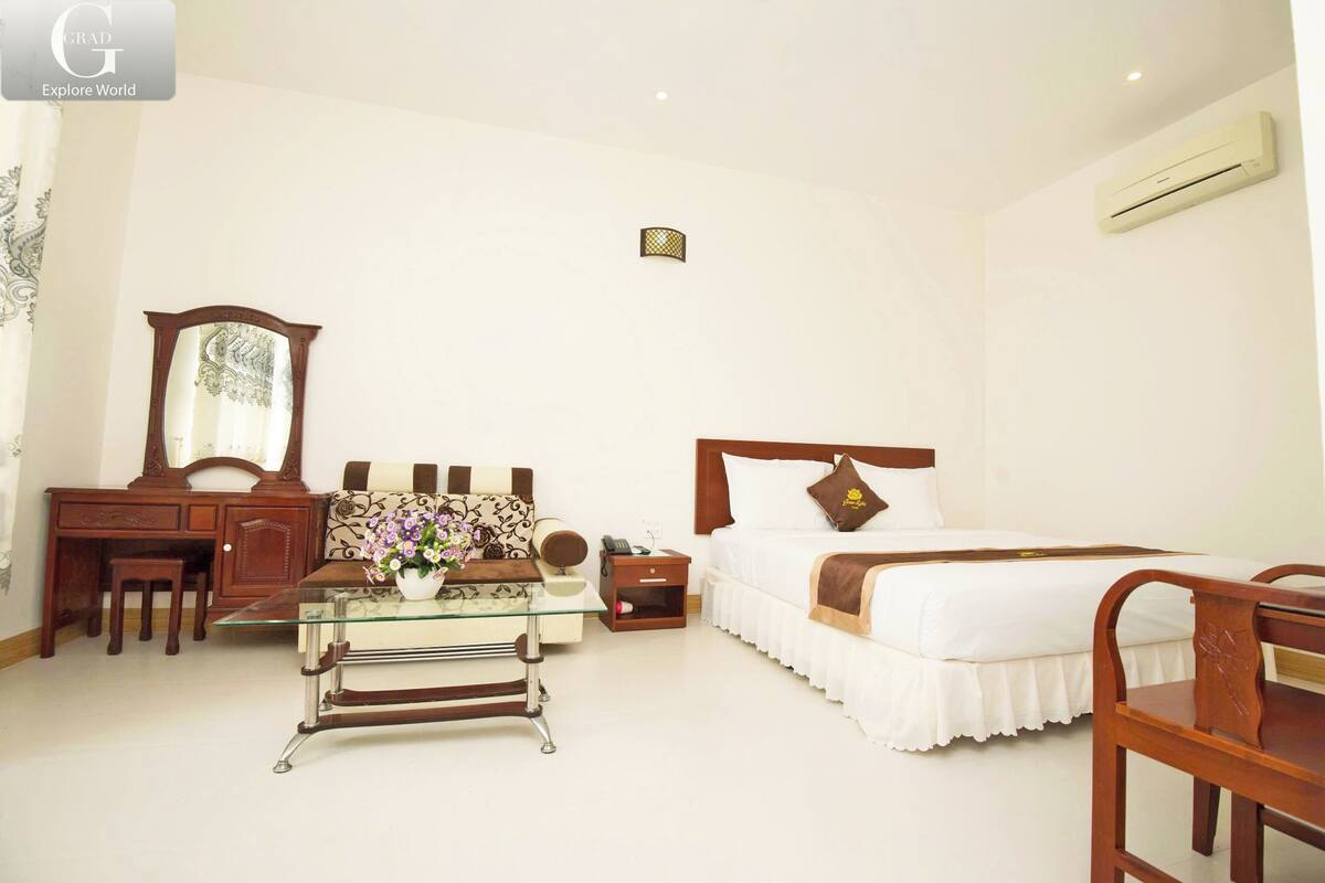 Une chambre d’hôtel comprenant un lit, un bureau, une chaise, une commode et un miroir.