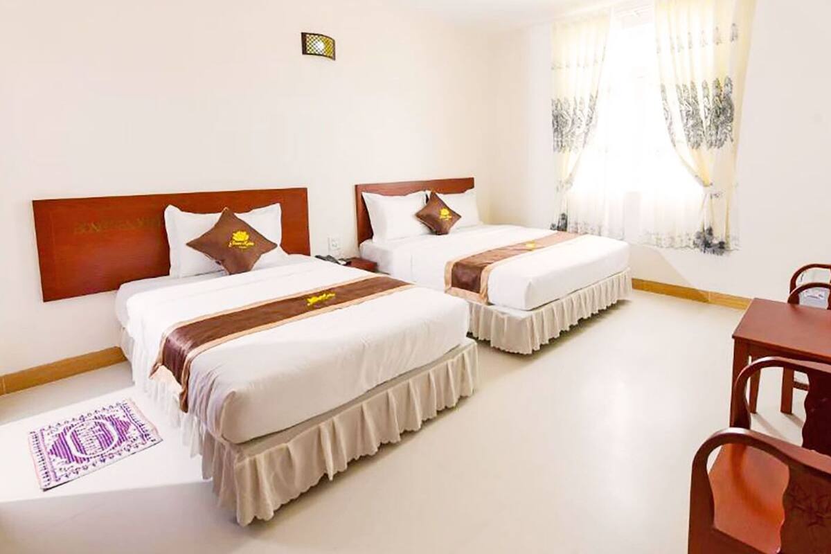 Une chambre d’hôtel avec deux lits, un bureau et une chaise.