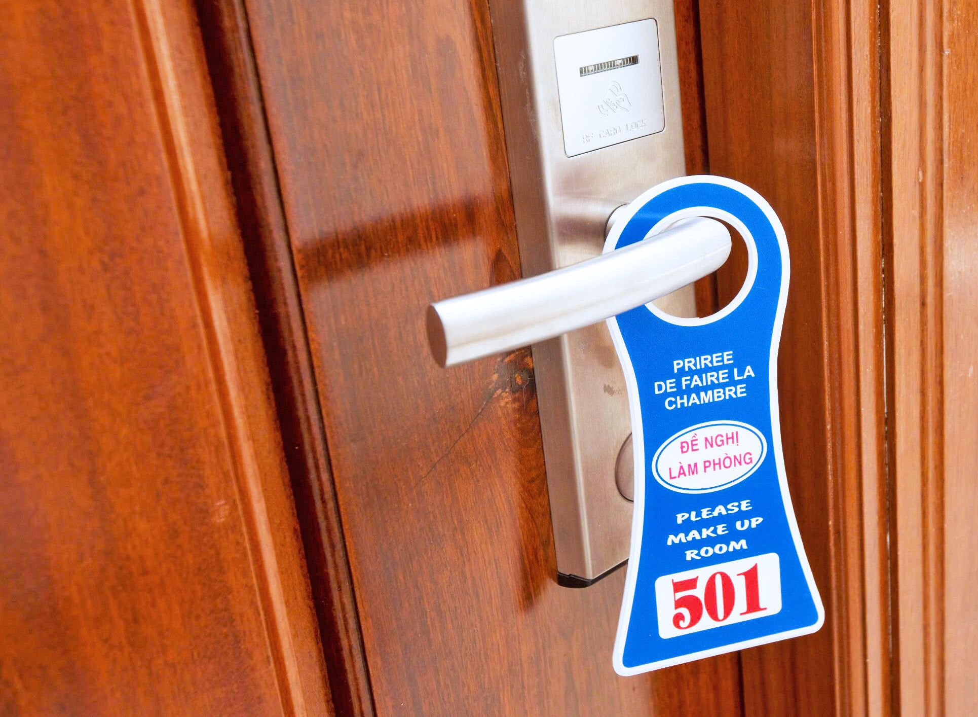 A hotel room door with a keycard lock and a blue keycard holder with text in French and English.