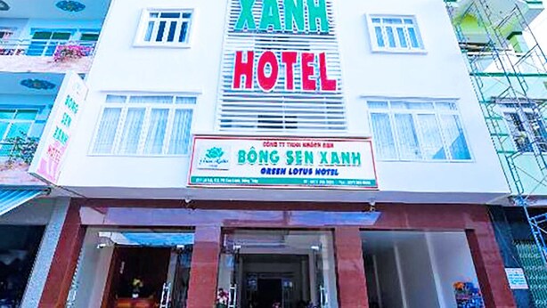 Un hotel con un cartel llamativo que dice "BONG SEN XANH HOTEL" y un cartel más pequeño debajo que indica "GREEN LOTUS HOTEL".