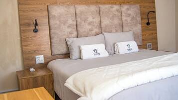 A neatly made bed with a wooden headboard, a bedside table with a power outlet, and a small wooden nightstand.