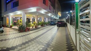 Entrada d'hotel amb sòl de rajola, plantes en testos i zona d'aparcament tancada per una reixa.