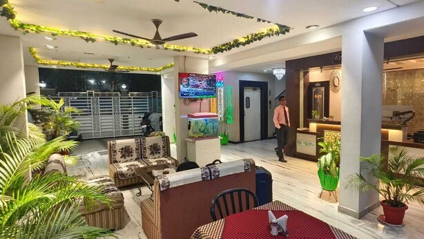 Un rebedor d'hotel espaiós amb zona de seients, taulell de recepció i pantalla de televisió.