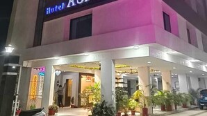Hotel anomenat "Hotel Asian", amb una entrada ben il·luminada i plantes en testos al davant.