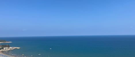 A coastal view with a beach, a road, and buildings.