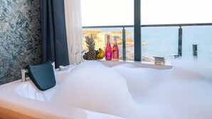 A bathtub with a view of the sea, a fruit bowl, and bottles on the windowsill. - Class Premium Hotel (Erdemli)